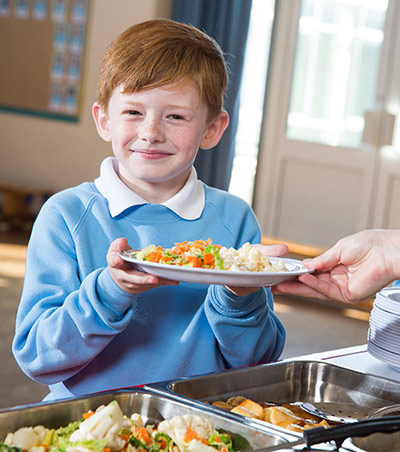 Young boy smiling receiving food for his lunch